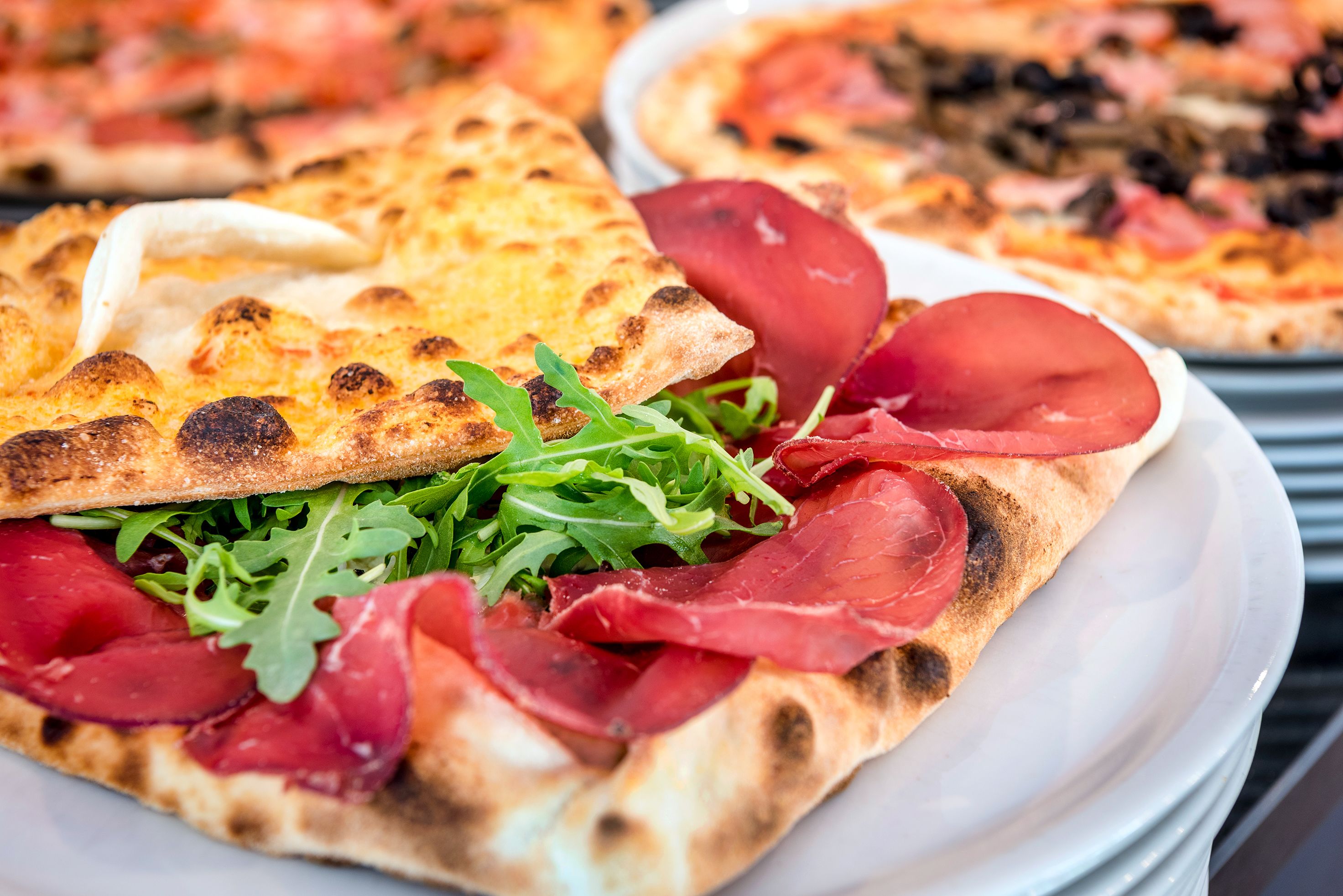 A variety of pizzas with different toppings, including one with arugula and prosciutto.