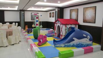 Children can play and relax in this vibrant play area, featuring a slide, playhouse, and foam blocks.