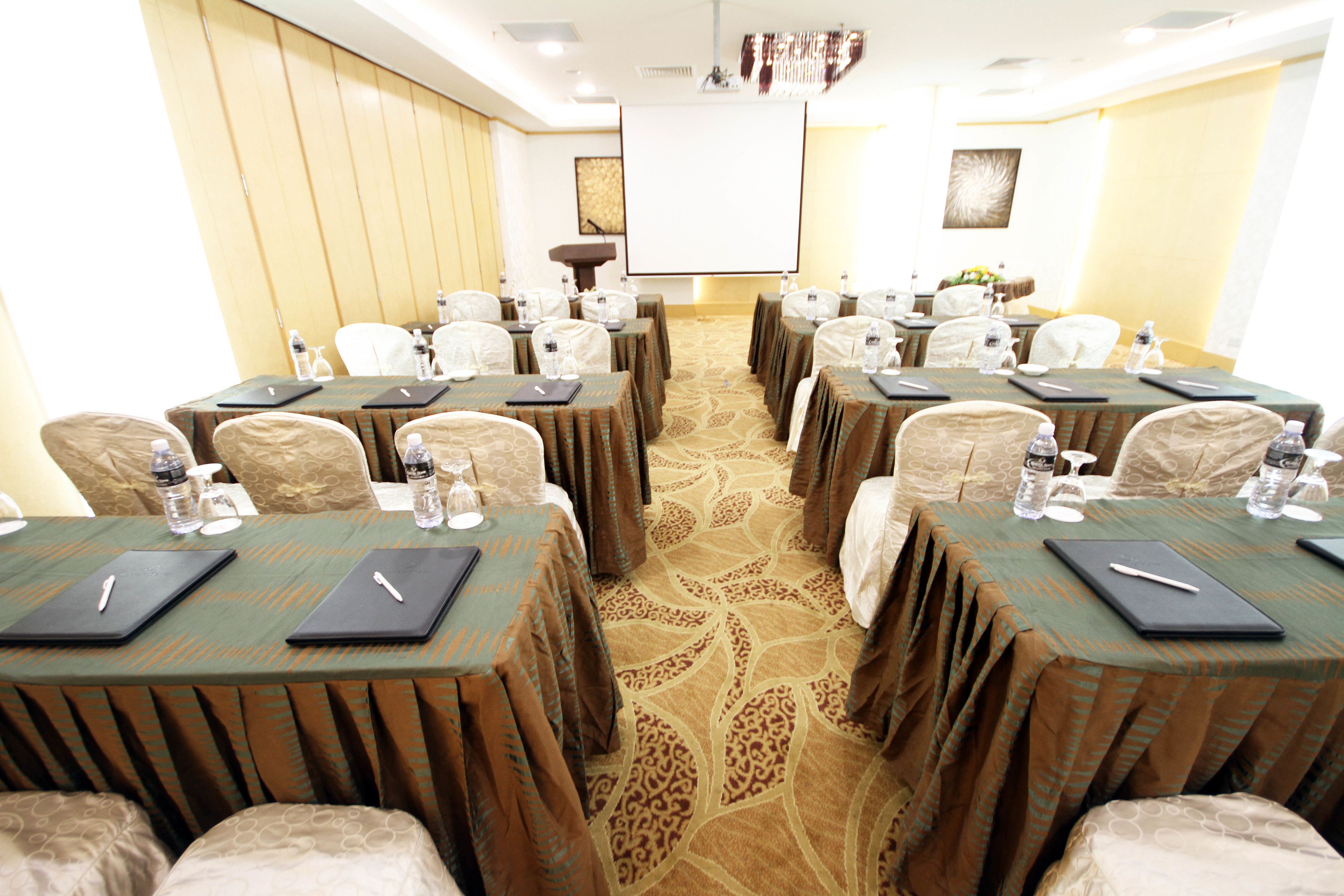 A conference room with multiple tables, each with a laptop, water bottle, and notepad.