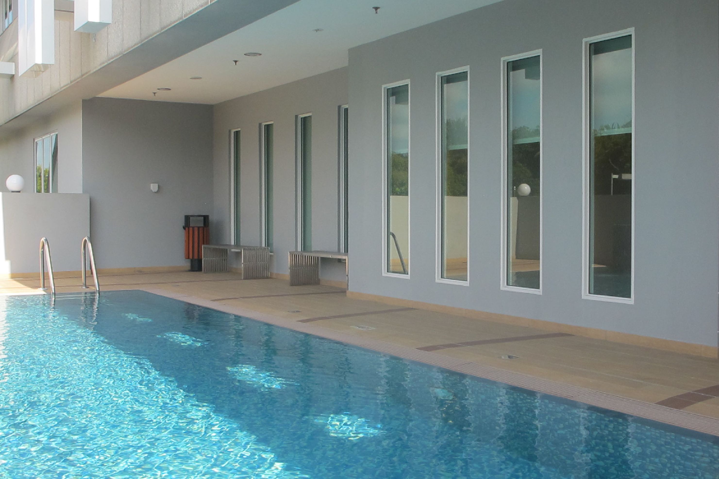 A modern indoor swimming pool with clear blue water, large windows, and a clean, minimalist design.