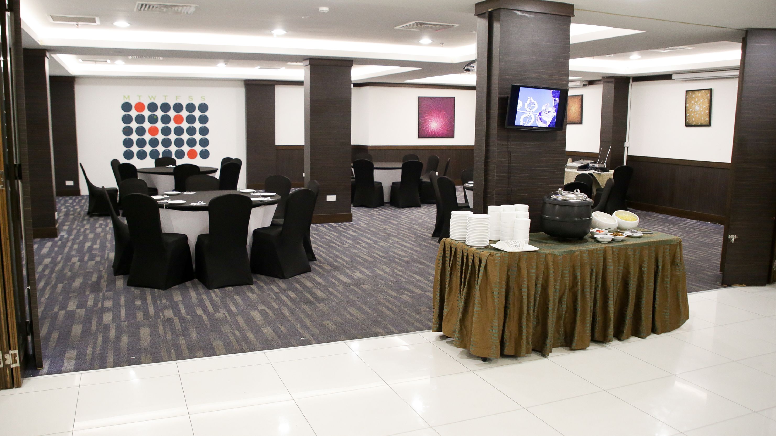 Una sala de conferències amb taules rodones, cadires i una barra de buffet amb diversos plats.