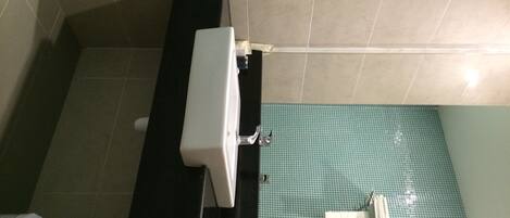 A bathroom with a black sink, a white toilet, and a green tiled floor.