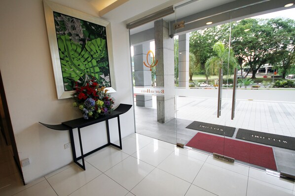 Un área de recepción con diseño moderno, que incluye un mostrador de recepción, un cuadro abstracto de gran tamaño y un felpudo en la entrada.