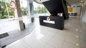 A reception area with a glass partition, a black reception desk with the hotel name, and a view of the outside. - Badi'ah Hotel (Bandar Seri Begawan)