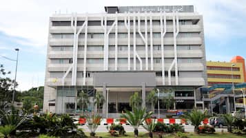 Un hotel moderno con una estructura de varios pisos, una entrada destacada y un jardín ajardinado en la parte delantera.