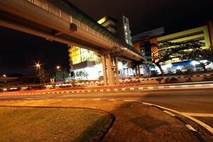 Escena urbana nocturna con un paso elevado de varios niveles, edificios iluminados y una carretera bien iluminada con vehículos en movimiento.