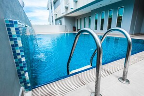 Una piscina interior moderna con agua azul cristalina, escaleras de metal y borde de azulejos.