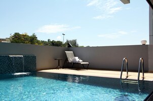 Una piscina al aire libre, sillones reclinables de piscina