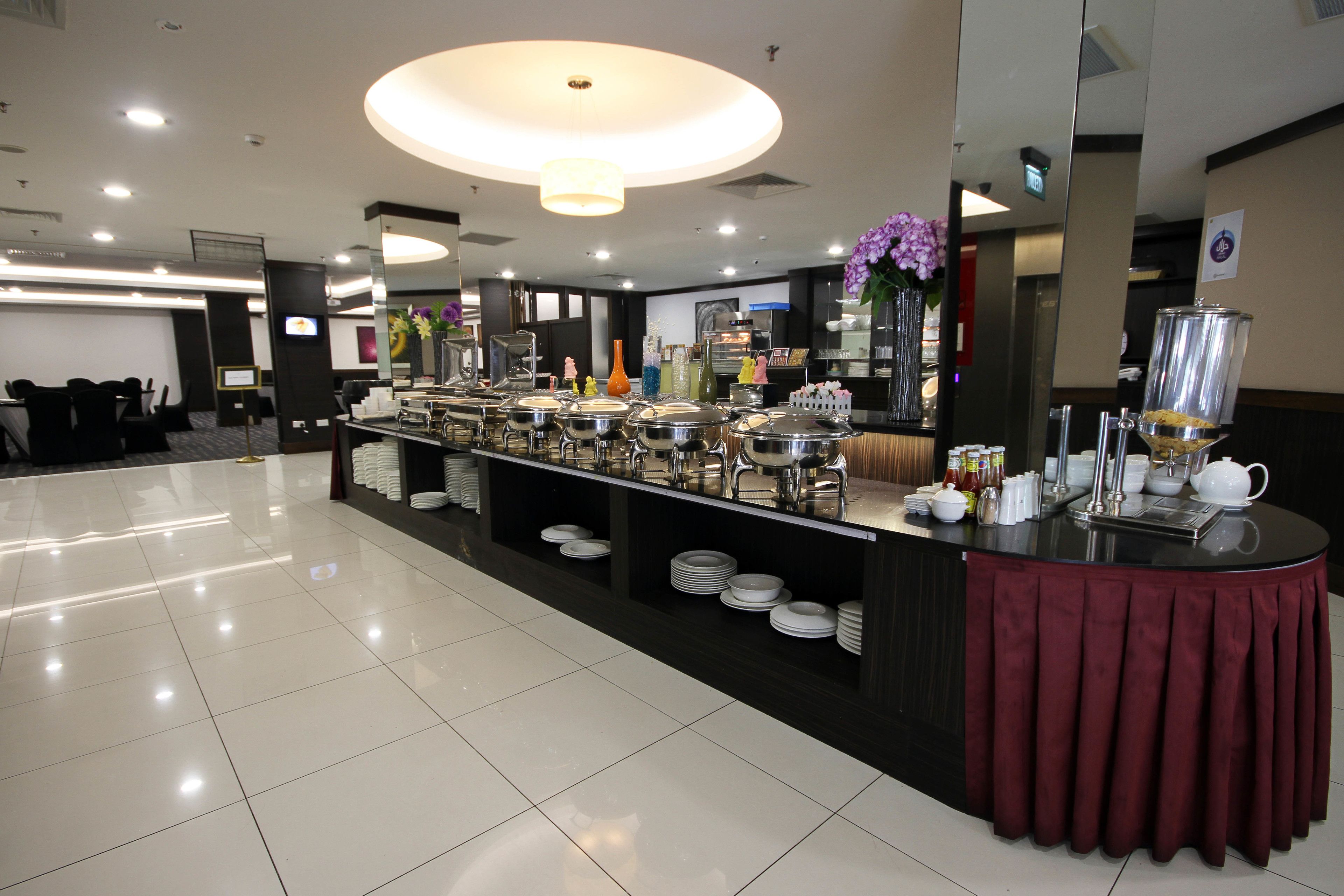 A buffet setup with multiple serving stations, a central counter with a red tablecloth, and a modern interior design.