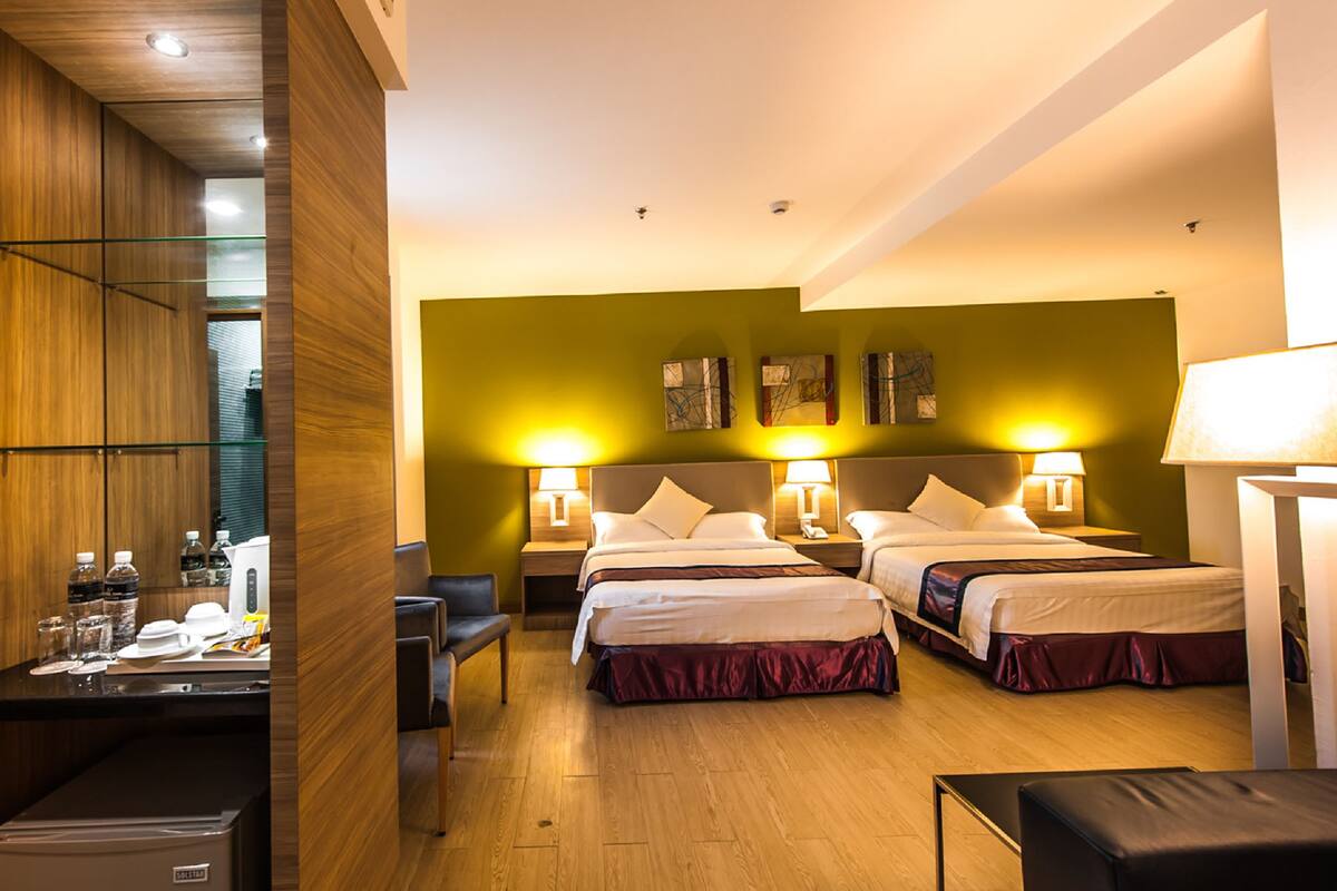 A hotel room with two beds, a desk with a computer, and a small seating area.