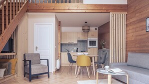 A modern kitchen with wooden cabinets, a dining area with a table and chairs, and a staircase leading to an upper level. - Le Clos du 5 - Appart Hotel Bagneres (Bagnères-de-Bigorre)