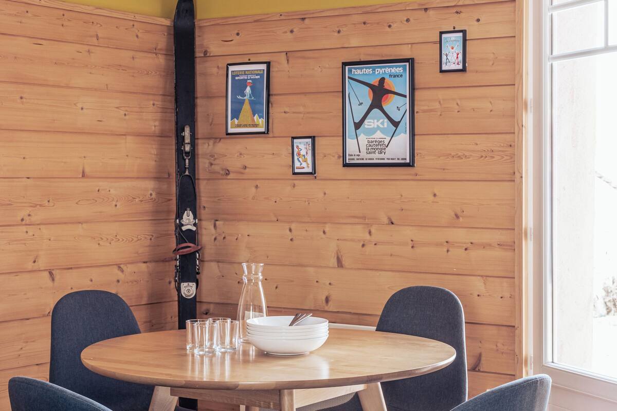 Ein Essbereich mit einer Holzwand, einem runden Tisch und blauen Stühlen.