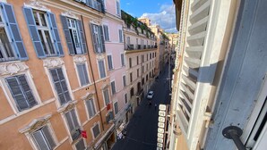 A narrow street lined with historic buildings, featuring balconies and traditional shutters. - Frattina 57 (Rome)