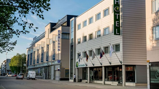 Een hotel met een moderne gevel, diverse vlaggen en een heldere lucht.