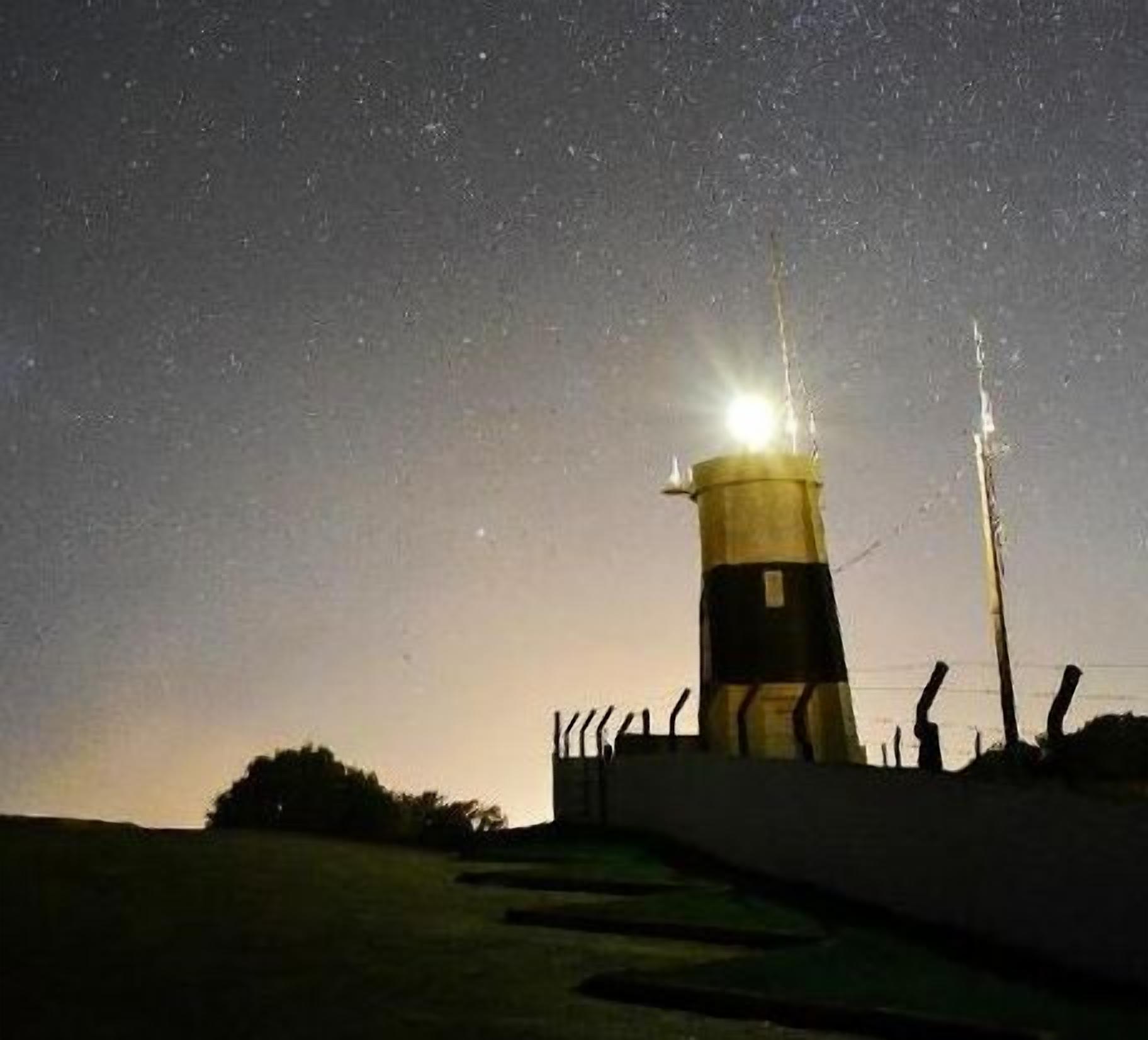 Un faro de noche bajo un cielo despejado.