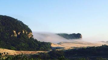Un paisaje natural con un valle, acantilados y una zona boscosa.