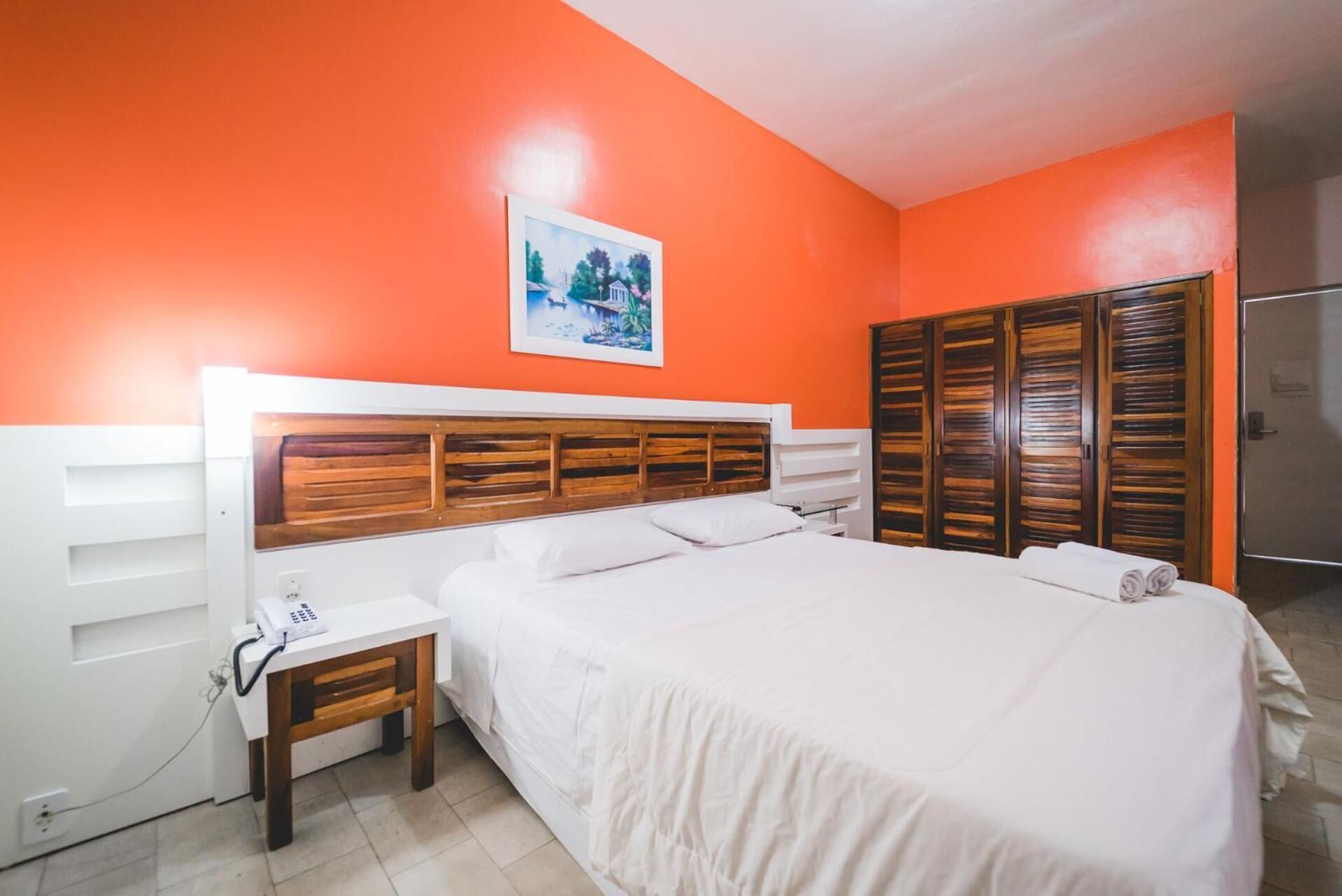 Un dormitorio con cama, mesita de noche, teléfono y armario.
