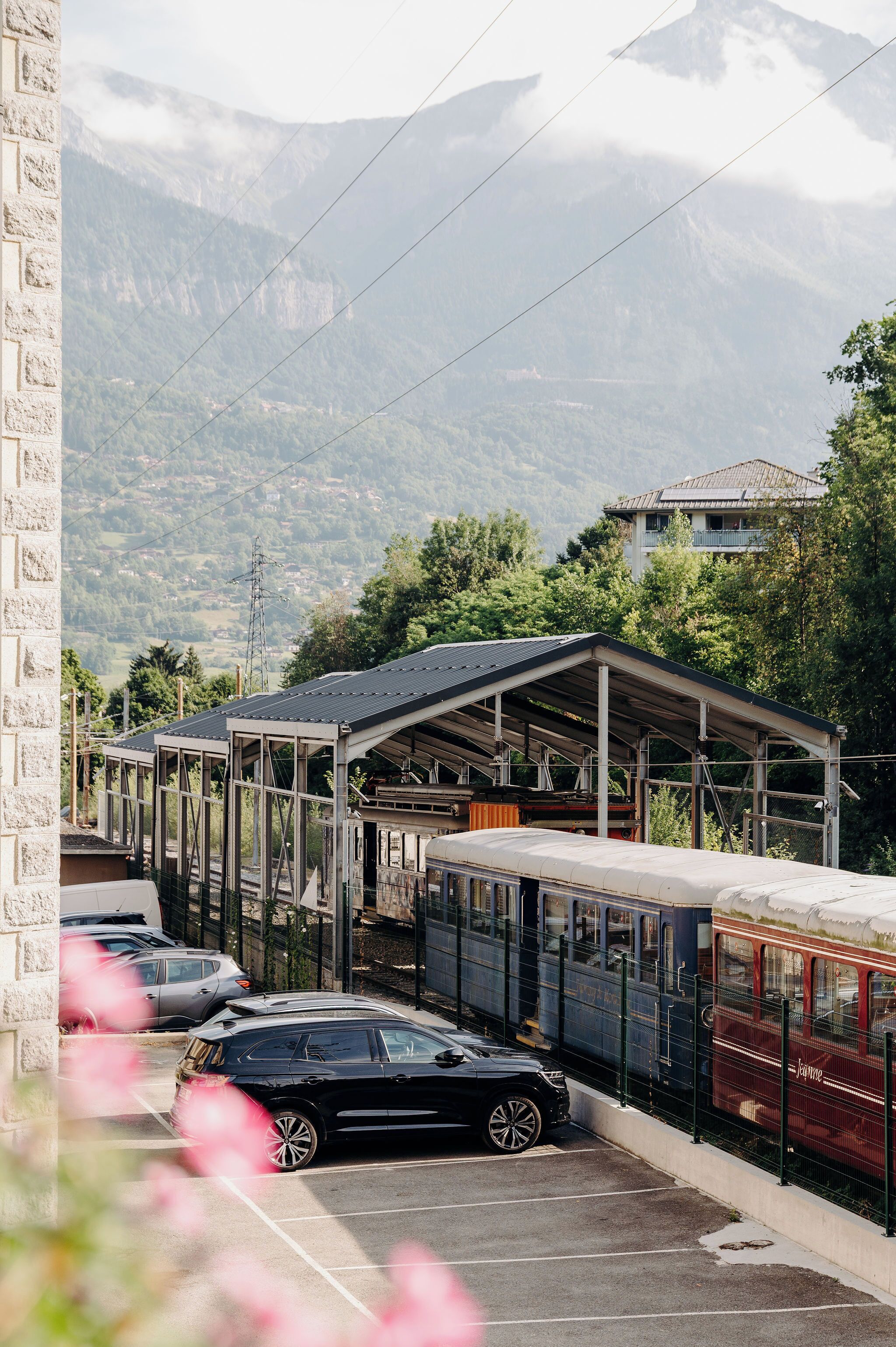 A parking area with a covered bus station and a mountain backdrop.
