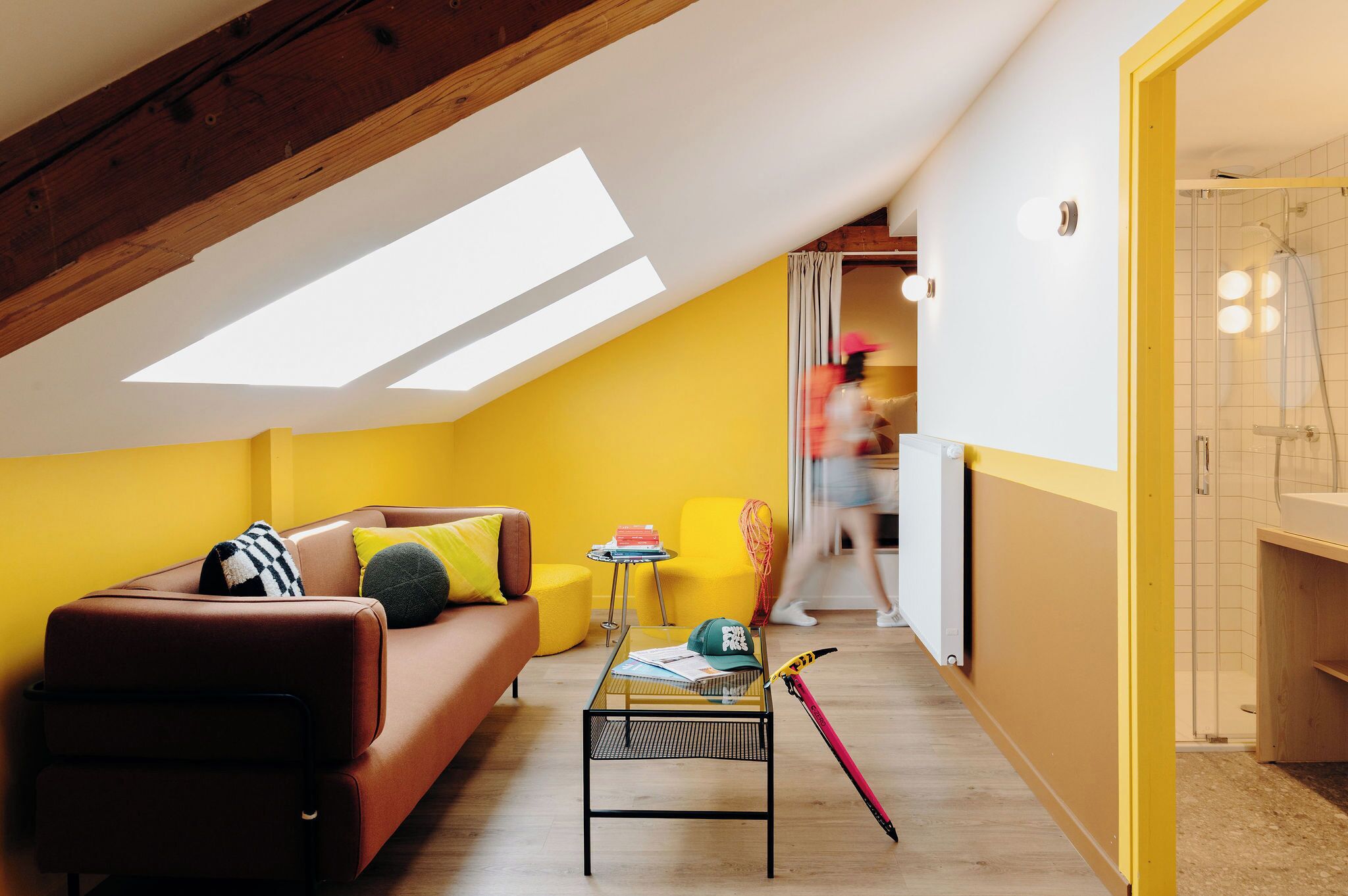 Un salon moderne doté d’un plafond en pente, d’un canapé, d’une table basse et d’un espace douche visible.