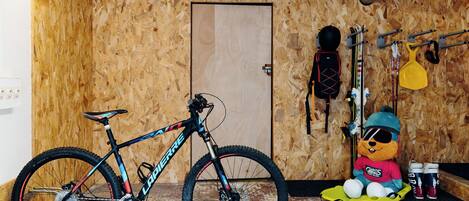 Une pièce avec un mur en bois, une porte, un vélo et un jouet en peluche.