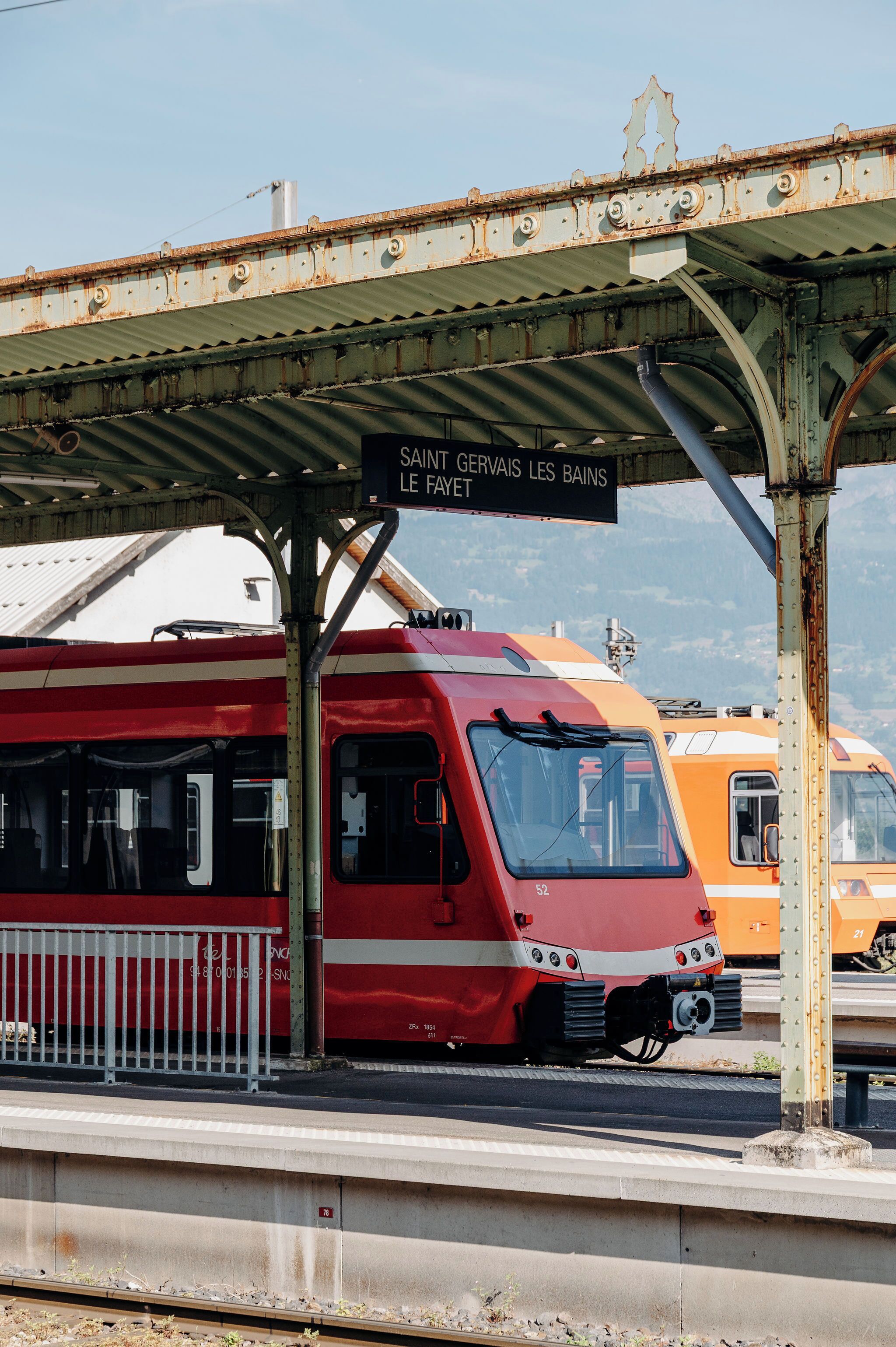 A red and white train at a station with a sign reading 'SAINT GERVAIS LES BAINS LE FAYET'.