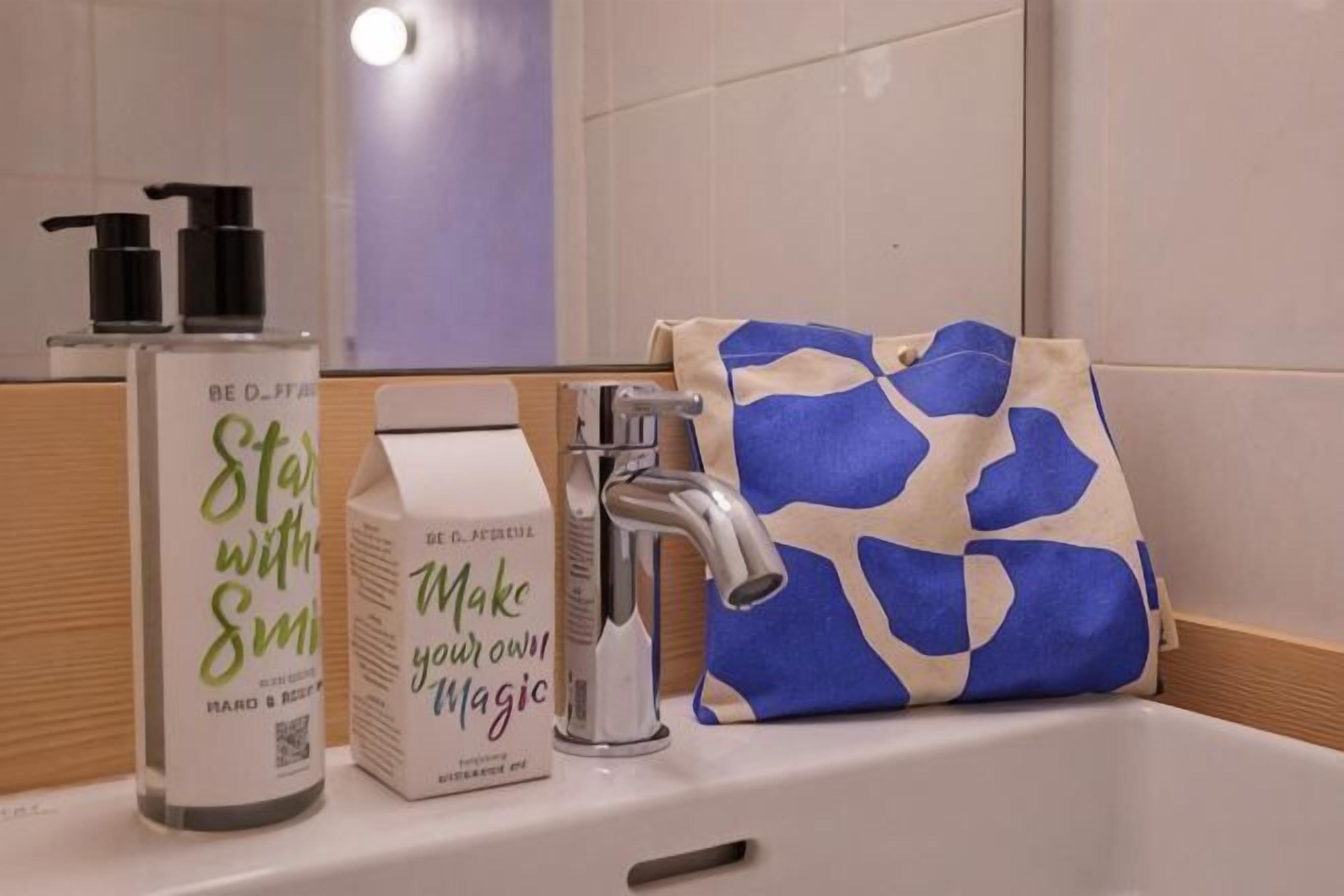 Ein Waschbecken mit Spiegel, eine Handseife, eine Taschentuchbox und eine taschenförmige Aufbewahrung in blau-weißem Muster.