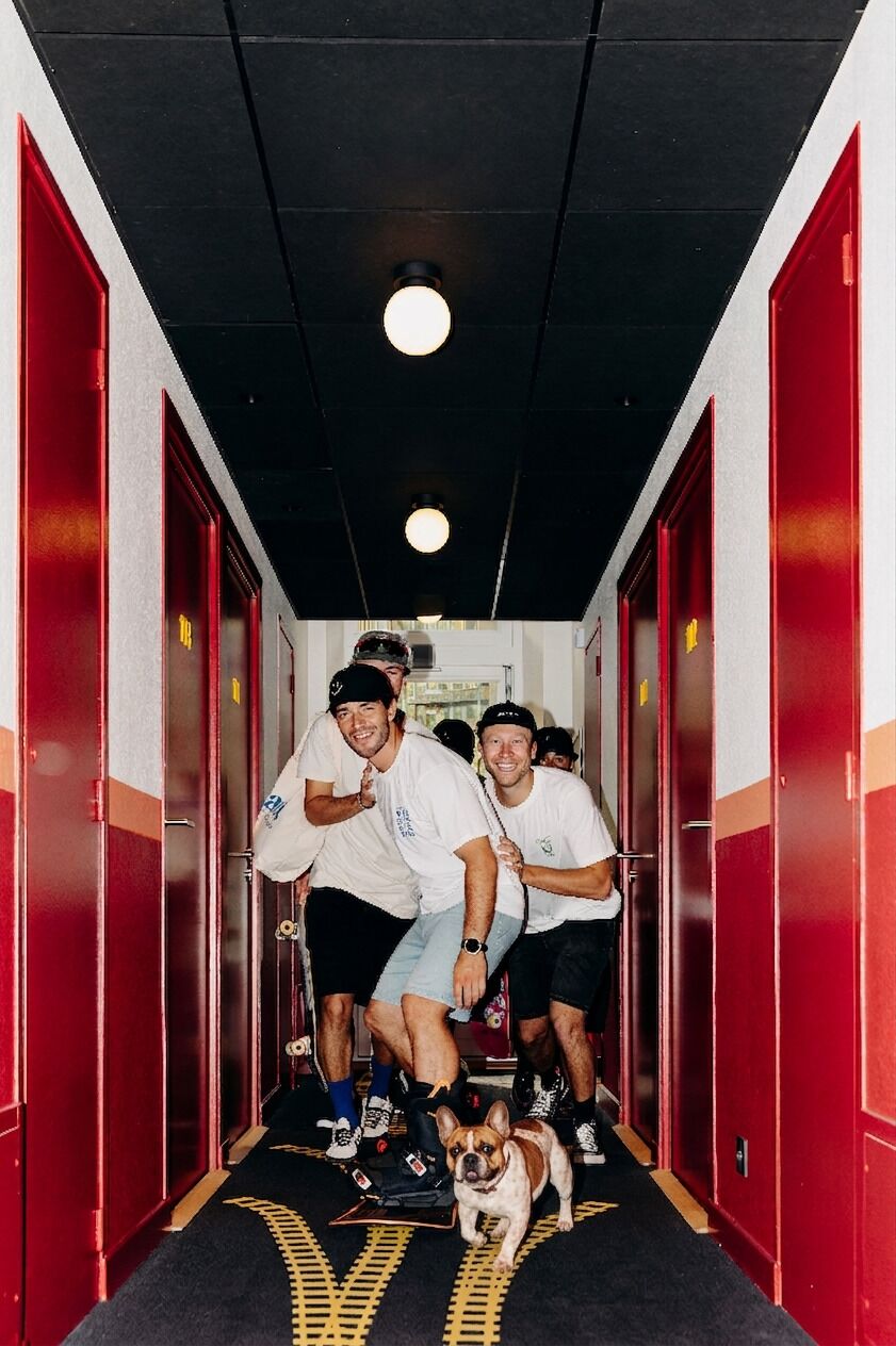 A hallway with red lockers, a dog, and people in athletic wear.