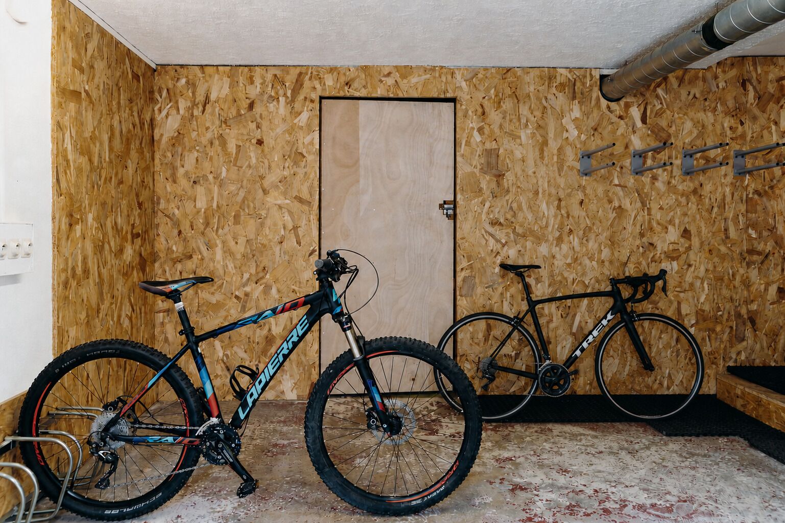 A room with wooden walls, a door, and two bicycles.