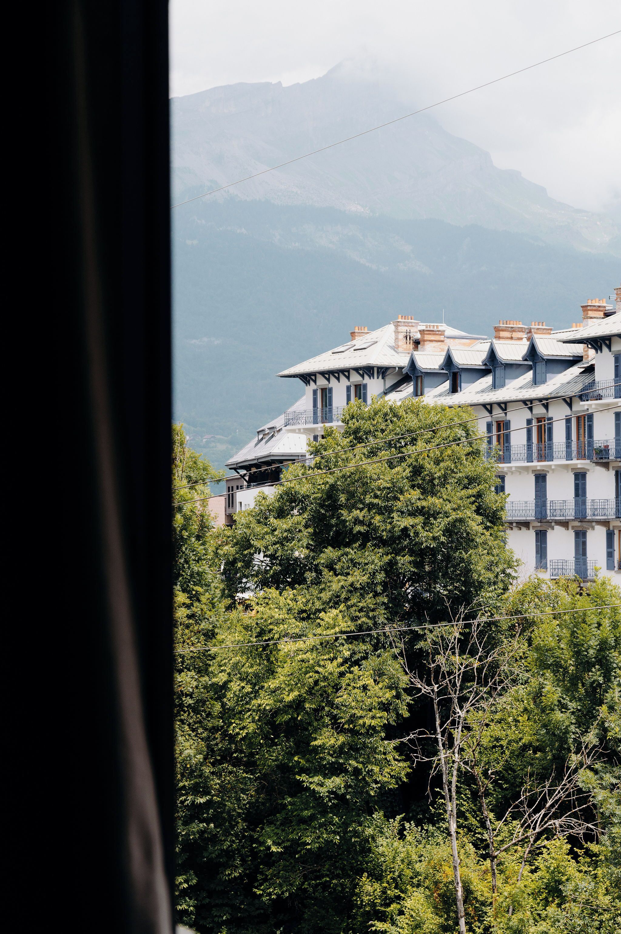 Ein Gebäude mit mehreren Balkonen und einer Bergkulisse.