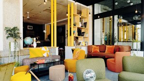 A modern lounge area with vibrant yellow and green furniture, a globe, and a bookshelf. - PlanB Hotel - Living Saint Gervais (Saint-Gervais-les-Bains)