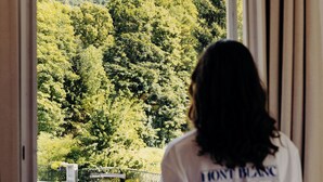 A person standing by a window with a view of a forested hillside. - PlanB Hotel - Living Saint Gervais (Saint-Gervais-les-Bains)