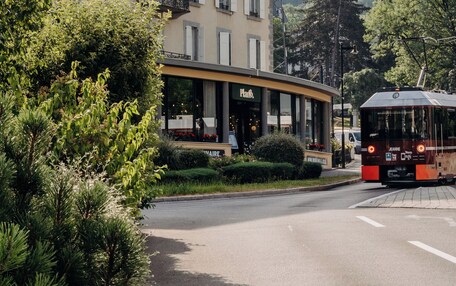 A building with a curved facade, a sign that reads "Hotel", and a tram in the foreground.