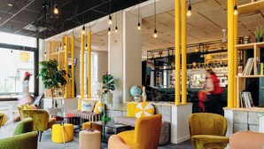 A modern interior with yellow and green chairs, a bar area, and a visible plant. - PlanB Hotel - Living Saint Gervais (Saint-Gervais-les-Bains)