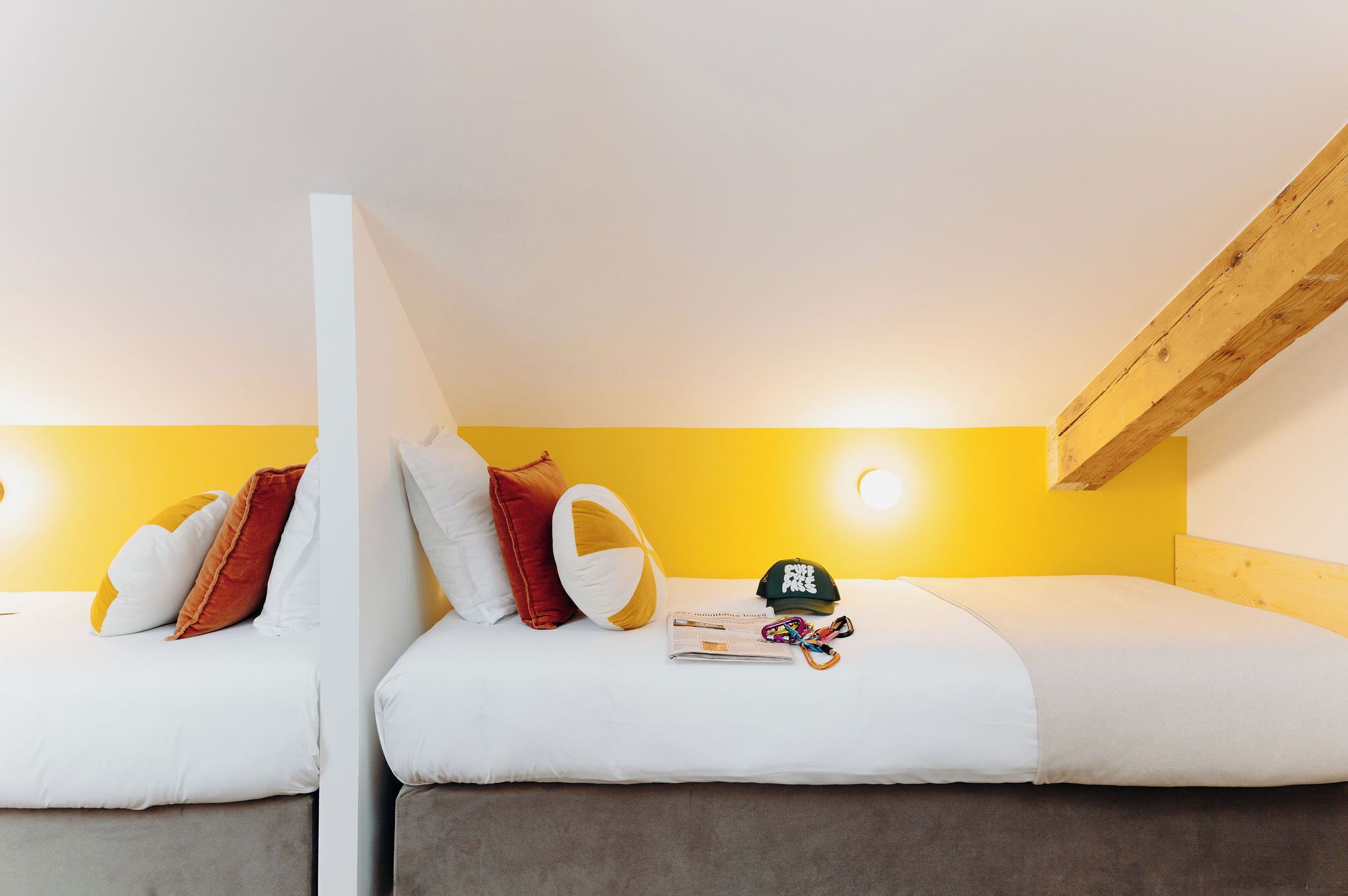 Una habitación con dos camas, paredes amarillas y una viga de madera en el techo.