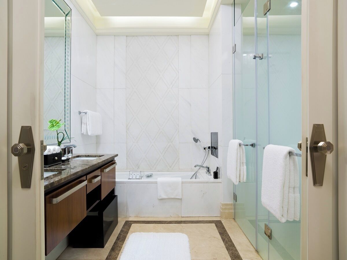 A modern bathroom with a glass shower enclosure, a bathtub, and a vanity with a marble countertop.