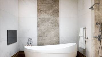 A modern bathroom with a freestanding bathtub, a shower area, and a marble floor.