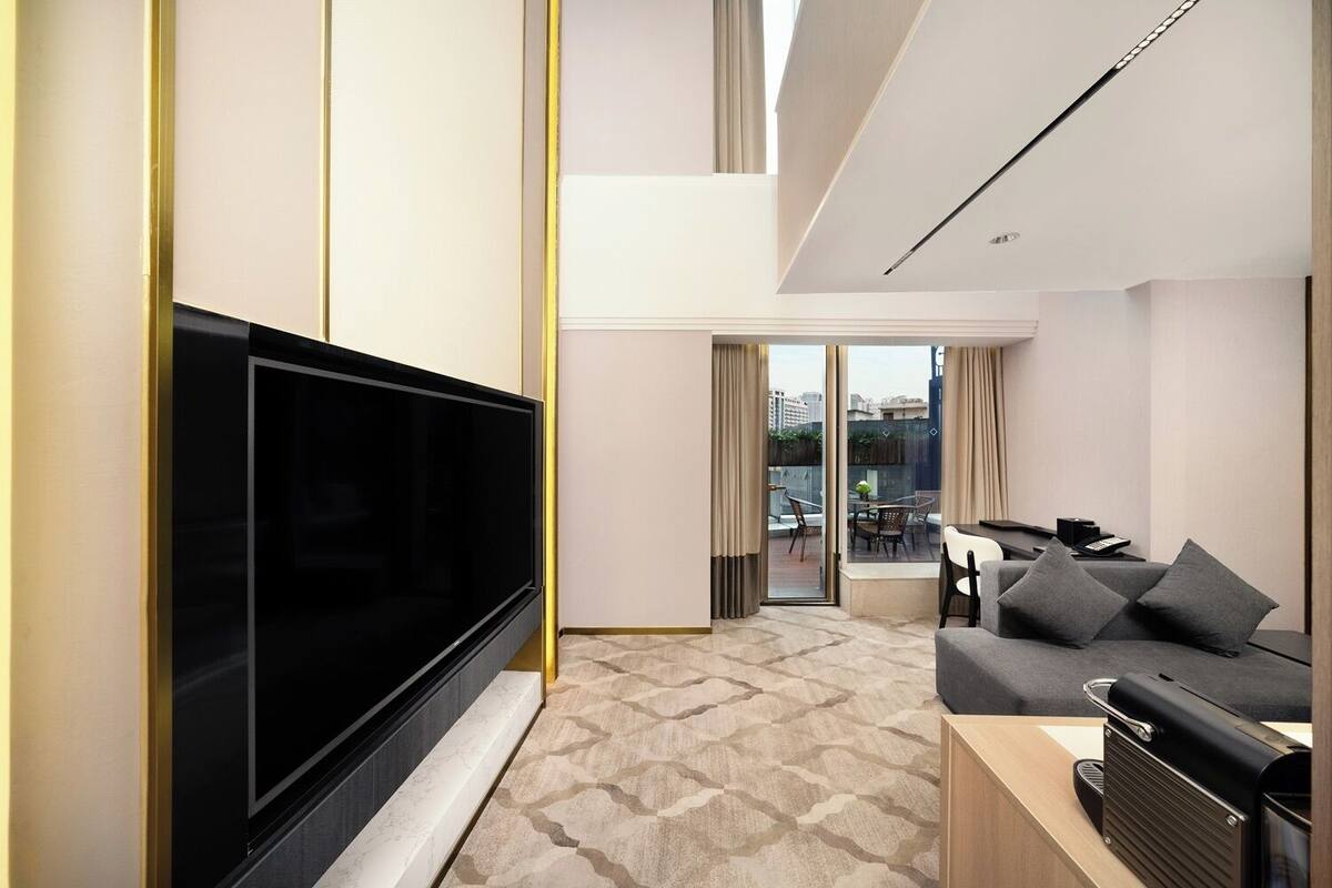A modern living room with a flat-screen TV, a sofa, a coffee table, and a grill.