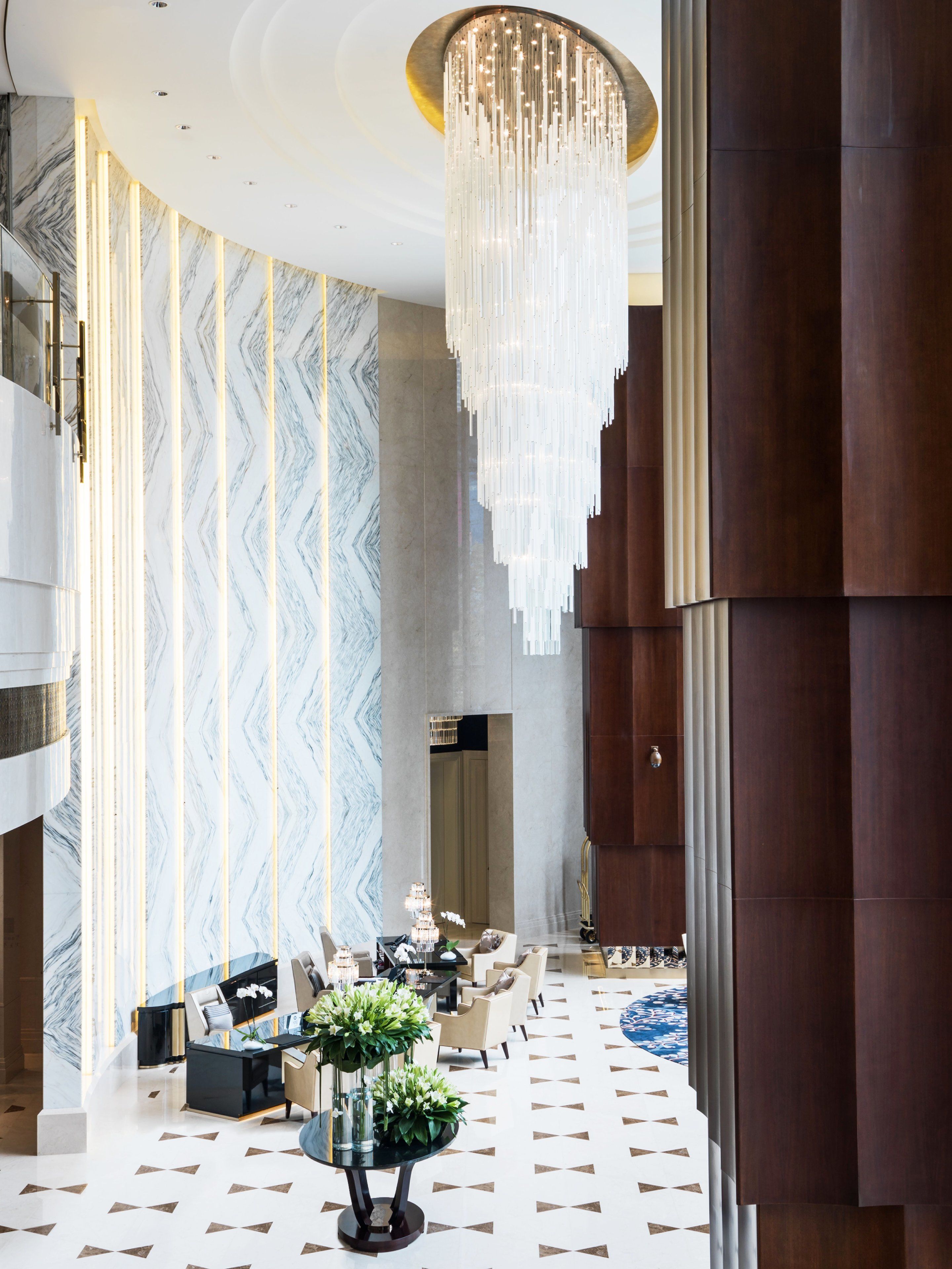 Een ruime lobby met een hoog plafond, een grote kroonluchter en een vloer met een patroon.