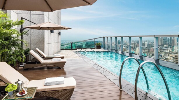 A rooftop infinity pool with lounge chairs and umbrellas, overlooking a cityscape. - The St. Regis Chengdu (Chengdu)