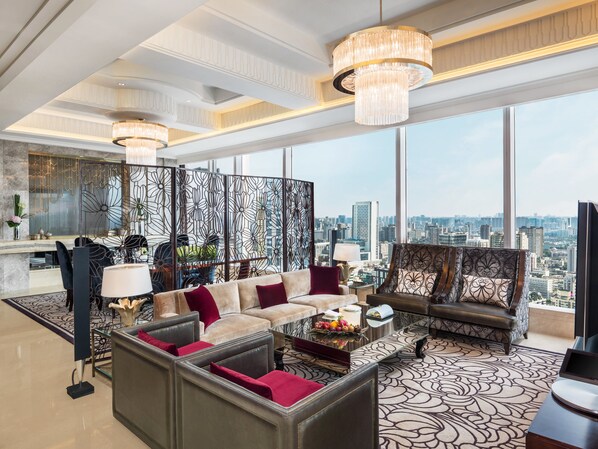 Un amplio salón con vista a la ciudad, un gran candelabro y un moderno conjunto de sofás.