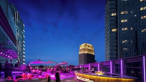 A rooftop bar with a wooden bar counter and seating area, surrounded by modern buildings and a clear sky. - The St. Regis Chengdu (Chengdu)