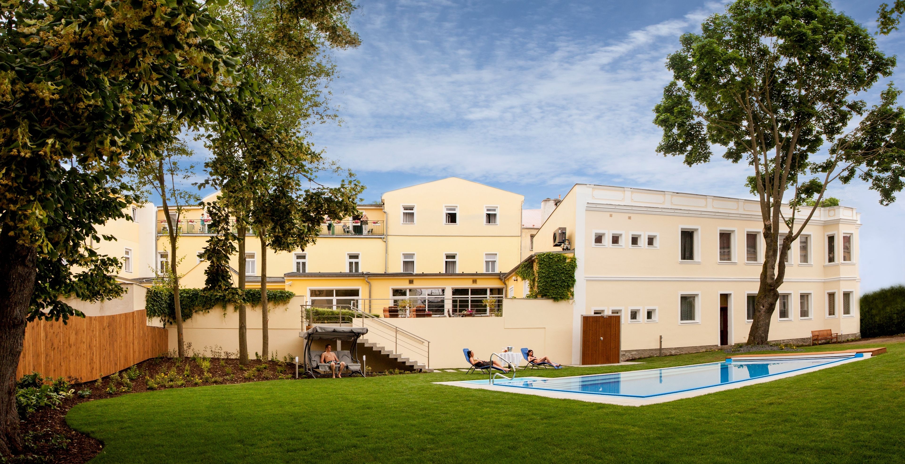 Un edificio de dos pisos con piscina, un área de estar techada y una escalera que conduce al nivel superior.
