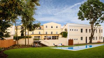 Un edificio de dos pisos con piscina, un área de estar techada y una escalera que conduce al nivel superior.
