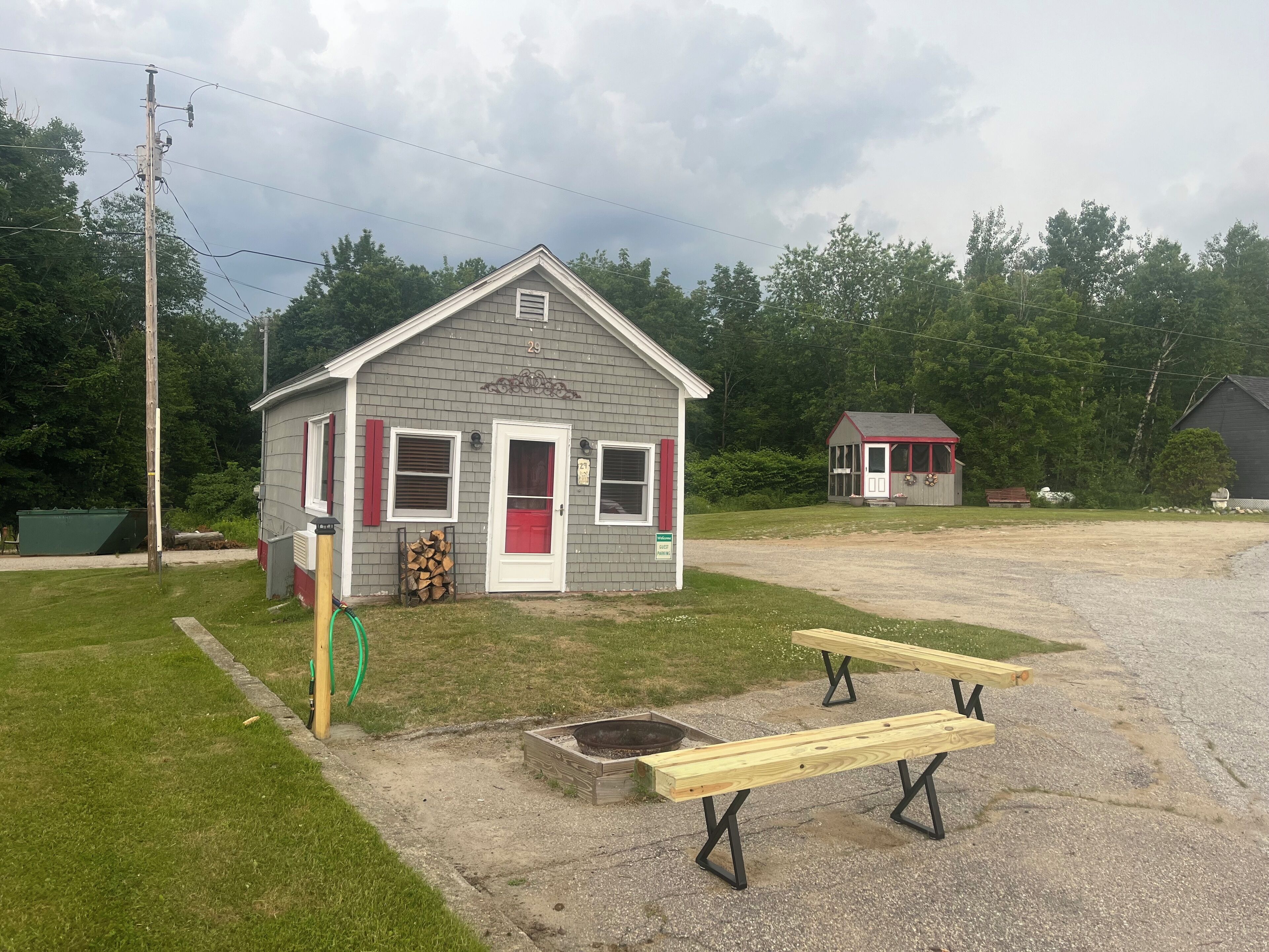 A small, single-story building with a red door and white trim, number 29, adjacent to a larger structure with a red roof.