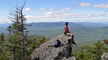A person sitting on a rock with a backpack, overlooking a mountainous landscape.
