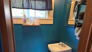 A bathroom with a toilet, sink, and window with a curtain.