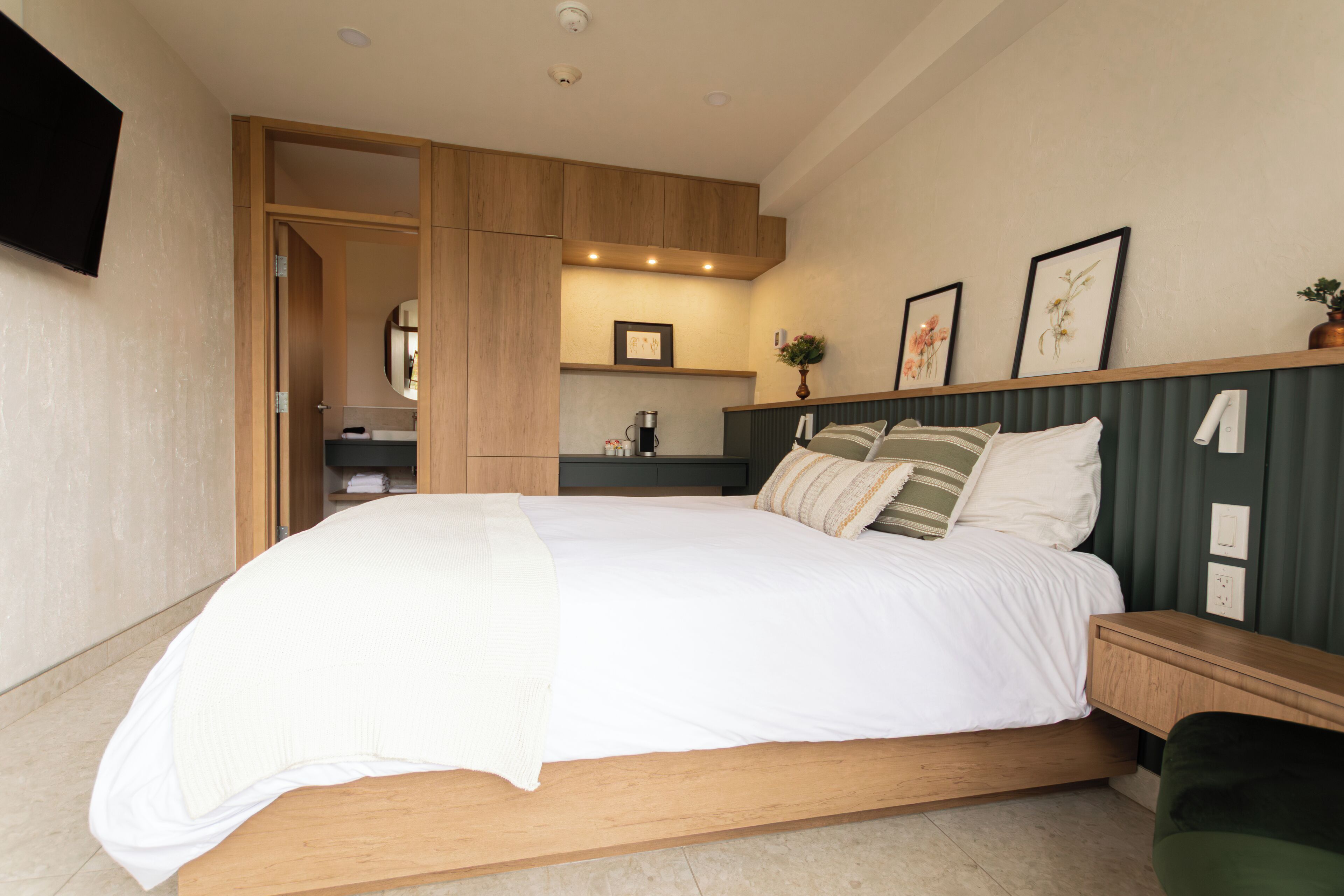 Une chambre moderne avec un grand lit, une tête de lit en bois, des tables de chevet et une armoire intégrée.
