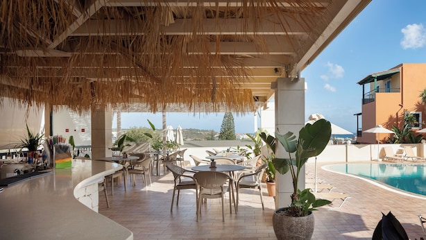 An outdoor bar area with a pool, lounge chairs, and potted plants. - Dia Apartments (Hersonissos)