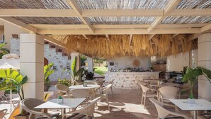 An outdoor patio area with wicker furniture, a stone wall, and a bar area. - Dia Apartments (Hersonissos)