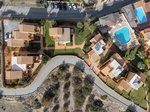 An aerial view of a residential area with multiple houses, a winding road, and a swimming pool. - Dia Apartments (Hersonissos)
